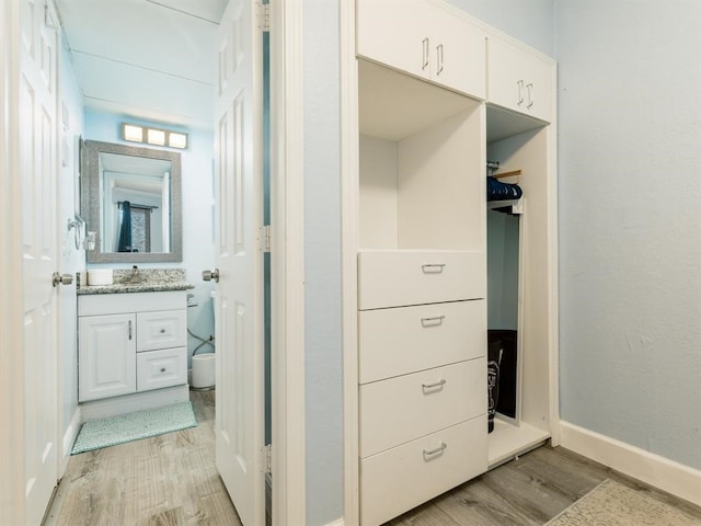 bathroom featuring vanity, wood finished floors, and baseboards