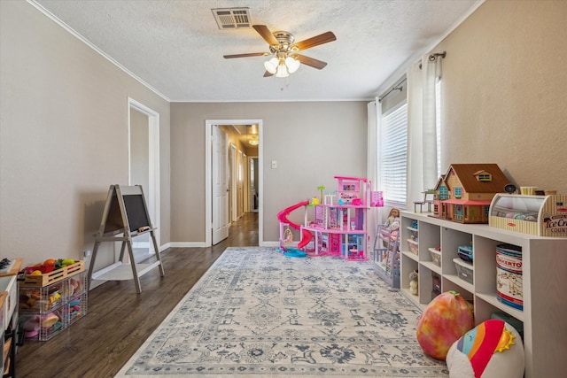 recreation room with dark wood-style floors, baseboards, visible vents, ceiling fan, and a textured ceiling