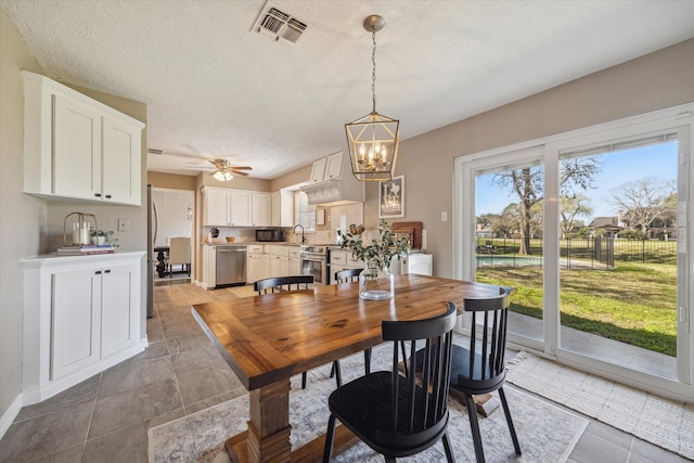 dining room with visible vents, baseboards, a textured ceiling, and ceiling fan with notable chandelier