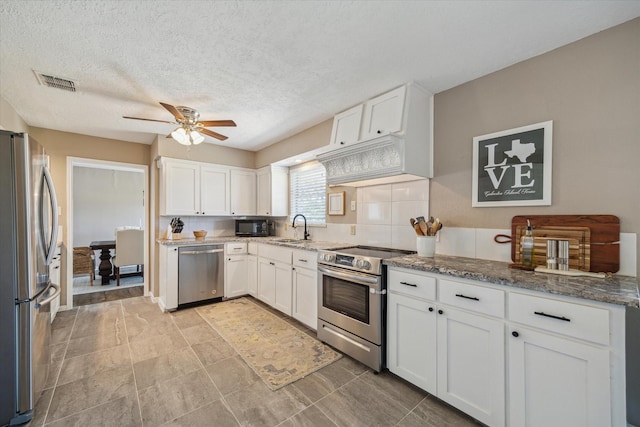 kitchen featuring visible vents, a sink, light stone counters, white cabinetry, and stainless steel appliances