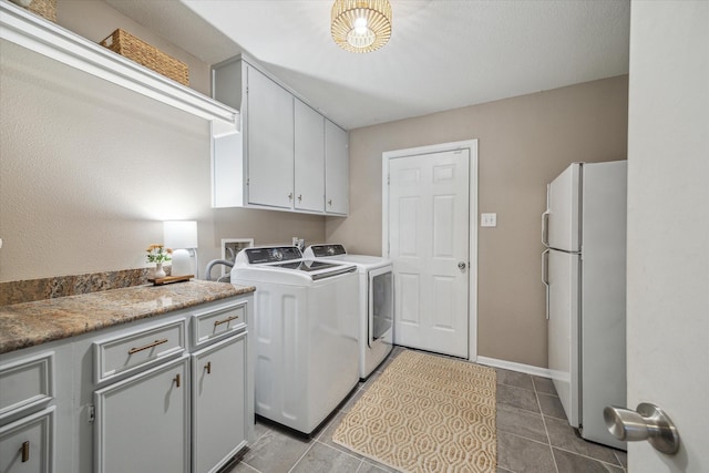 laundry area featuring washer and clothes dryer, cabinet space, tile patterned floors, and baseboards