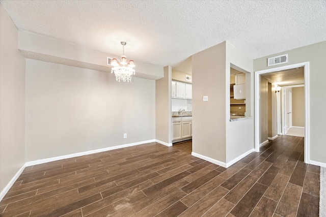 unfurnished dining area featuring visible vents, baseboards, wood tiled floor, a chandelier, and a sink