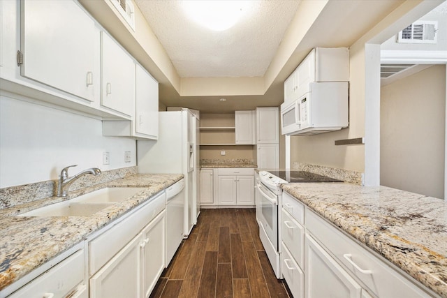 kitchen featuring white appliances, visible vents, dark wood finished floors, a sink, and white cabinets