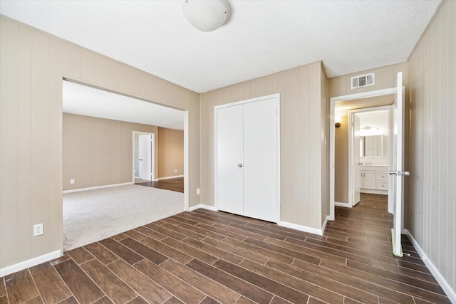 unfurnished bedroom with dark wood finished floors, visible vents, baseboards, and a closet