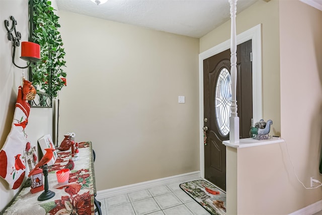 entrance foyer with baseboards, a textured ceiling, and light tile patterned flooring