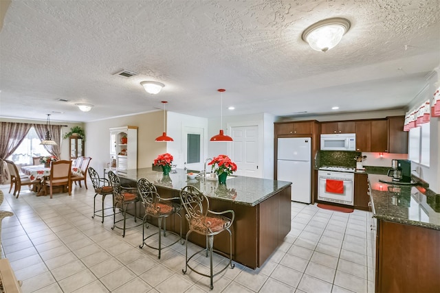 kitchen featuring white appliances, light tile patterned floors, visible vents, and dark stone counters