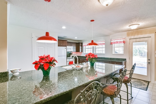 kitchen featuring a textured ceiling, white appliances, a healthy amount of sunlight, and a sink