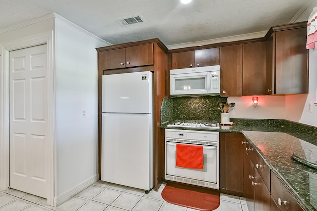 kitchen featuring light tile patterned floors, visible vents, white appliances, and dark stone countertops