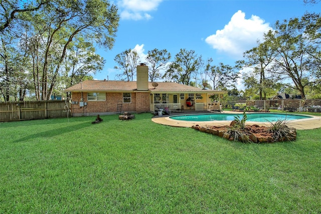 rear view of property featuring brick siding, a lawn, a chimney, and a fenced backyard