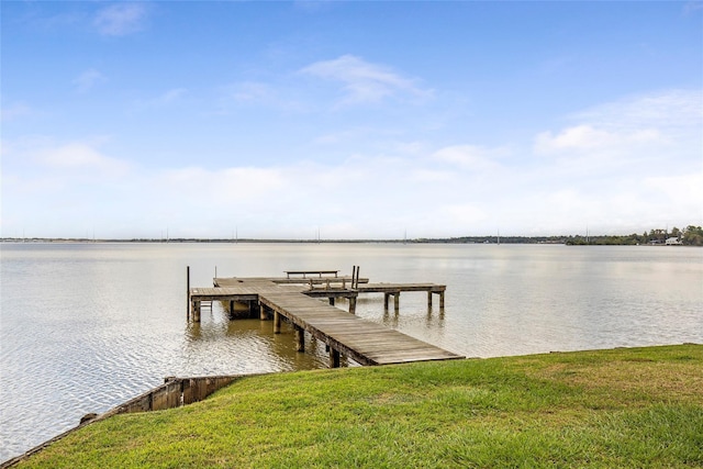 view of dock with a yard and a water view