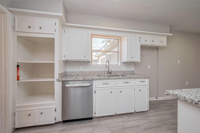 kitchen featuring a sink, tasteful backsplash, white cabinetry, light stone countertops, and dishwasher