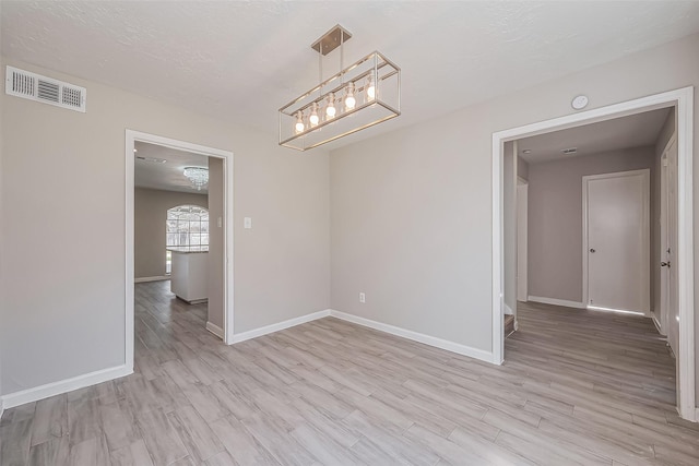 unfurnished dining area featuring baseboards, visible vents, and light wood finished floors