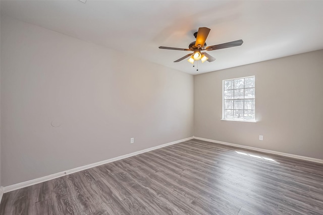 spare room with dark wood-style floors, ceiling fan, and baseboards