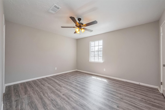 unfurnished room featuring visible vents, baseboards, wood finished floors, and a ceiling fan