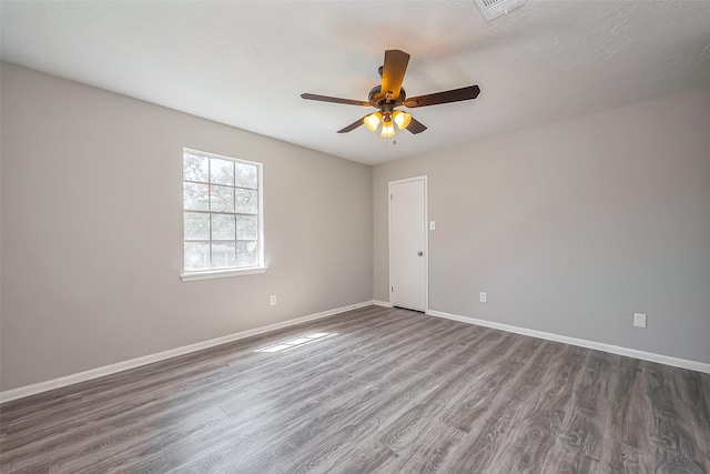 spare room with visible vents, baseboards, dark wood-style floors, and a ceiling fan