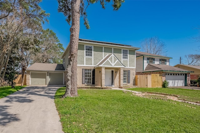 tudor house with a front yard, an attached garage, stucco siding, concrete driveway, and brick siding