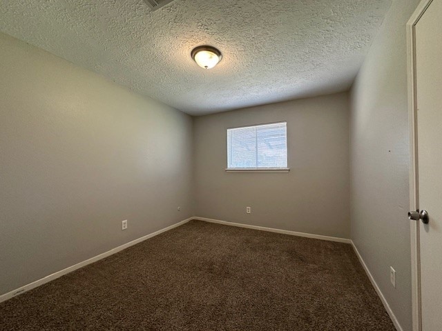 carpeted empty room featuring a textured ceiling and baseboards