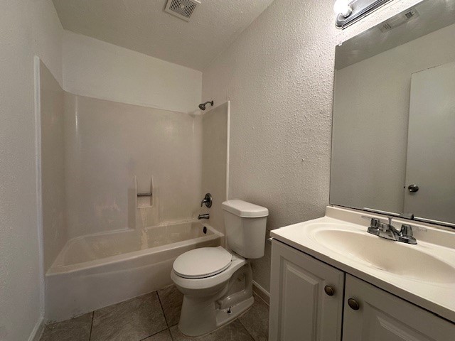 bathroom featuring visible vents, toilet, vanity, tile patterned floors, and a textured ceiling