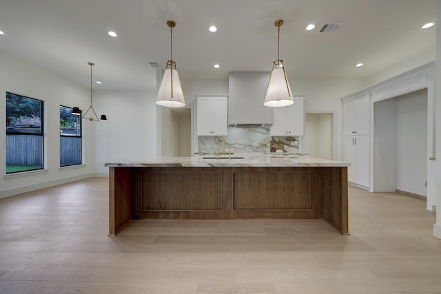 kitchen featuring visible vents, backsplash, white cabinets, light wood finished floors, and custom exhaust hood