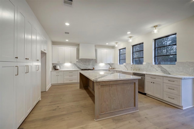 kitchen with visible vents, stainless steel dishwasher, light wood finished floors, decorative backsplash, and custom exhaust hood