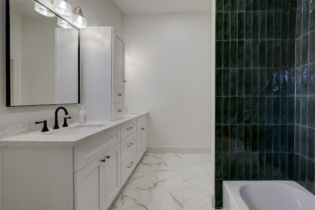 bathroom featuring marble finish floor, a sink, a tub, double vanity, and baseboards