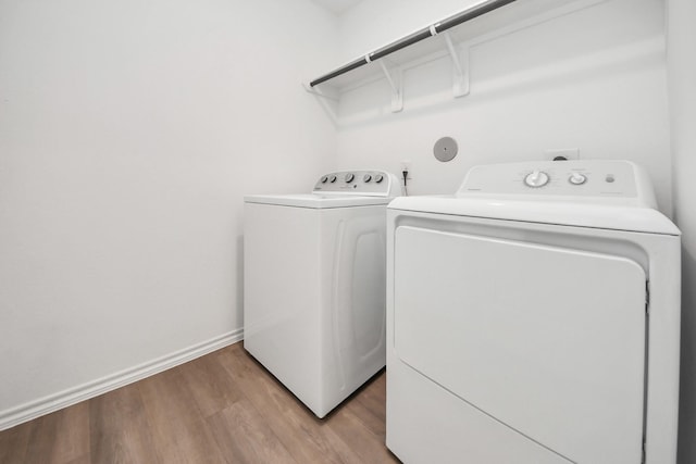 laundry area with laundry area, separate washer and dryer, light wood-type flooring, and baseboards