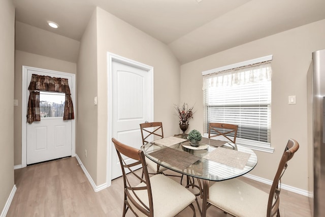 dining area featuring vaulted ceiling, light wood finished floors, baseboards, and a wealth of natural light