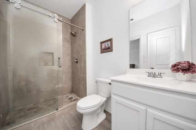 bathroom with wood finished floors, toilet, a stall shower, and vanity