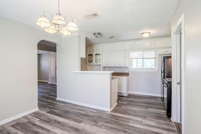 kitchen featuring black gas range oven, visible vents, arched walkways, dark wood-type flooring, and white cabinets