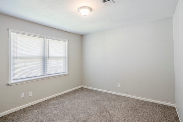 empty room featuring visible vents, baseboards, and carpet