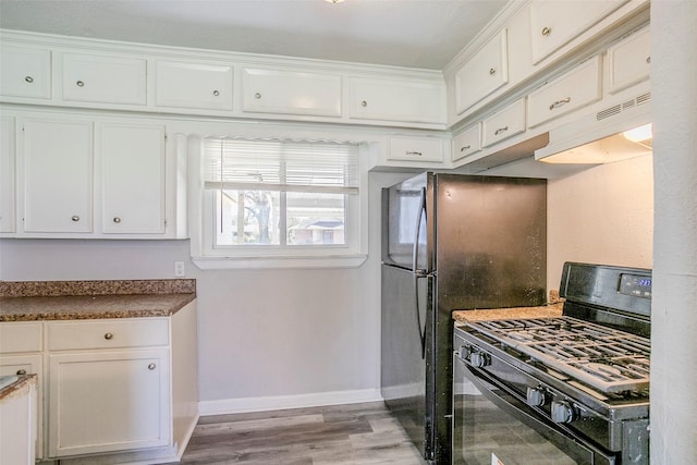 kitchen featuring under cabinet range hood, dark countertops, white cabinetry, black gas stove, and baseboards