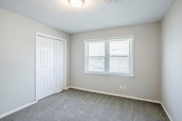 unfurnished bedroom with a closet, baseboards, carpet, and visible vents