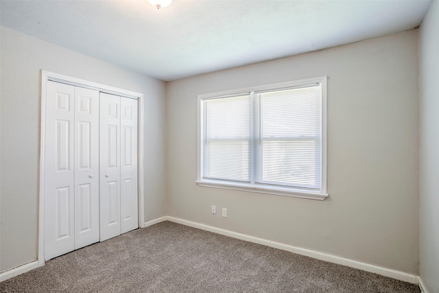 unfurnished bedroom with a closet, carpet flooring, and baseboards