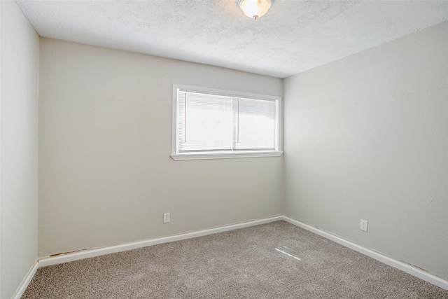 carpeted spare room featuring baseboards and a textured ceiling