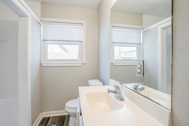 full bath featuring vanity, wood finished floors, baseboards, walk in shower, and toilet