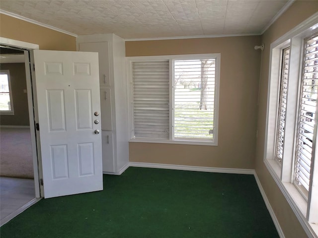 carpeted empty room featuring crown molding and baseboards