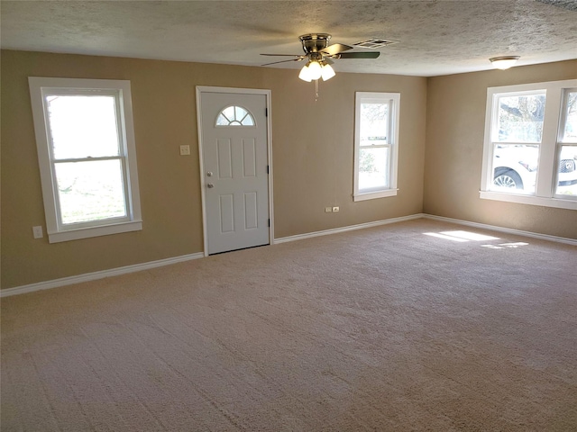 carpeted foyer entrance with visible vents, baseboards, and a textured ceiling