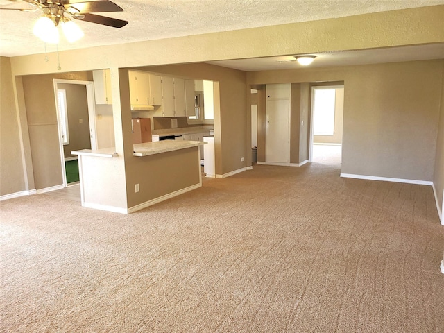 unfurnished living room with baseboards, light carpet, a textured ceiling, and ceiling fan