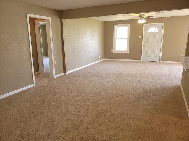 interior space with a ceiling fan, carpet flooring, visible vents, and baseboards