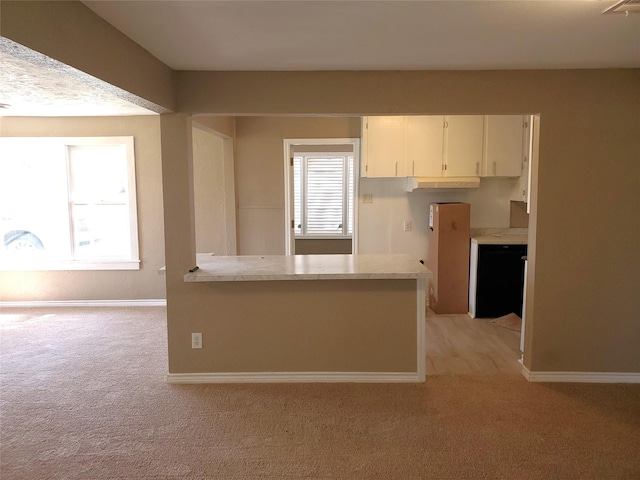 kitchen with white cabinetry, light countertops, baseboards, and light carpet