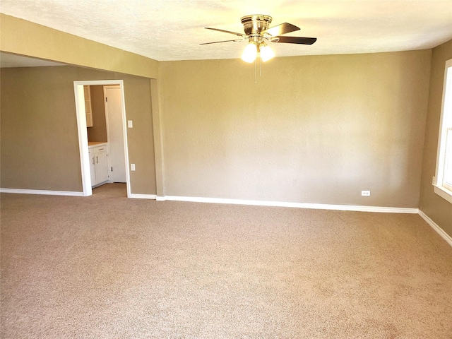 unfurnished room featuring baseboards, carpet floors, a textured ceiling, and a ceiling fan