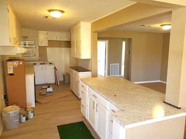 kitchen featuring a sink, visible vents, light wood-style floors, and white cabinets