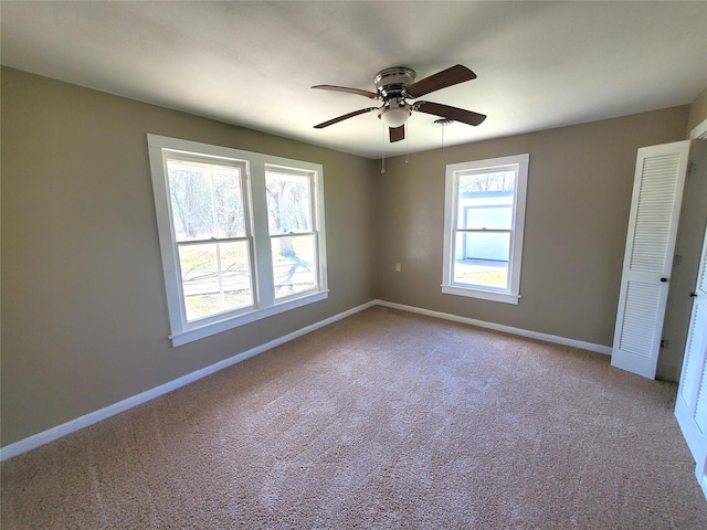 carpeted empty room featuring a ceiling fan and baseboards