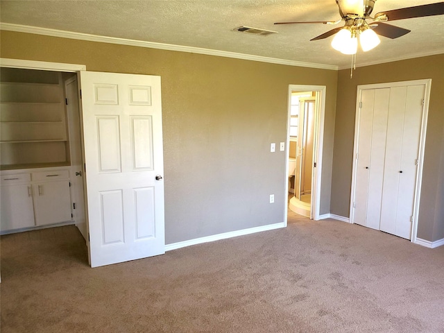 unfurnished bedroom with visible vents, a textured ceiling, carpet flooring, and crown molding