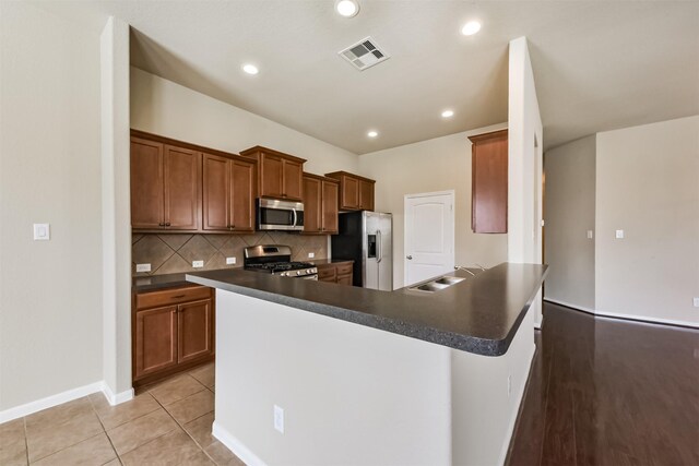 kitchen featuring visible vents, a sink, dark countertops, appliances with stainless steel finishes, and decorative backsplash