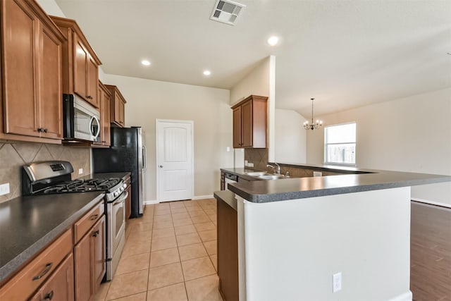 kitchen with dark countertops, visible vents, appliances with stainless steel finishes, and a sink