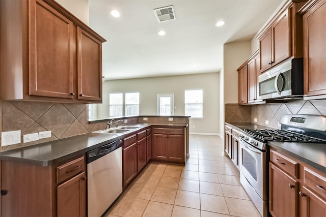 kitchen with visible vents, dark countertops, appliances with stainless steel finishes, a peninsula, and light tile patterned floors