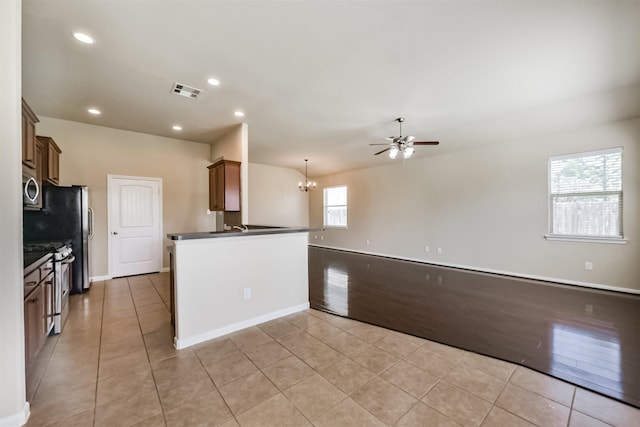 kitchen with light tile patterned floors, stainless steel appliances, dark countertops, and visible vents