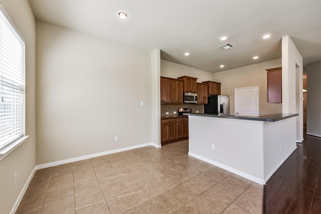 kitchen featuring stainless steel appliances, plenty of natural light, dark countertops, and visible vents