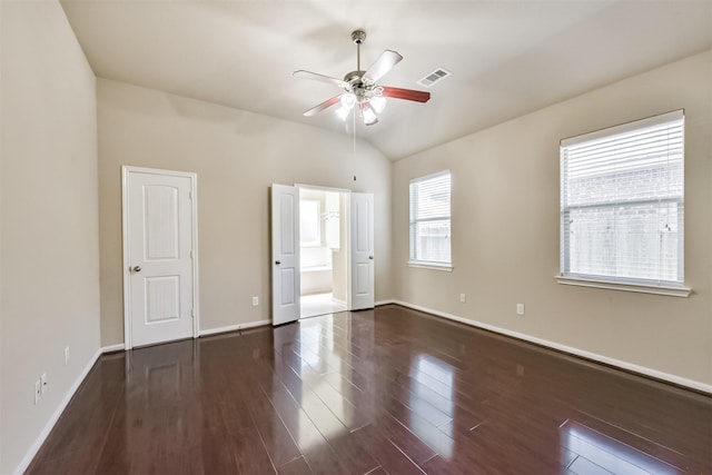 unfurnished bedroom featuring visible vents, dark wood finished floors, connected bathroom, baseboards, and vaulted ceiling